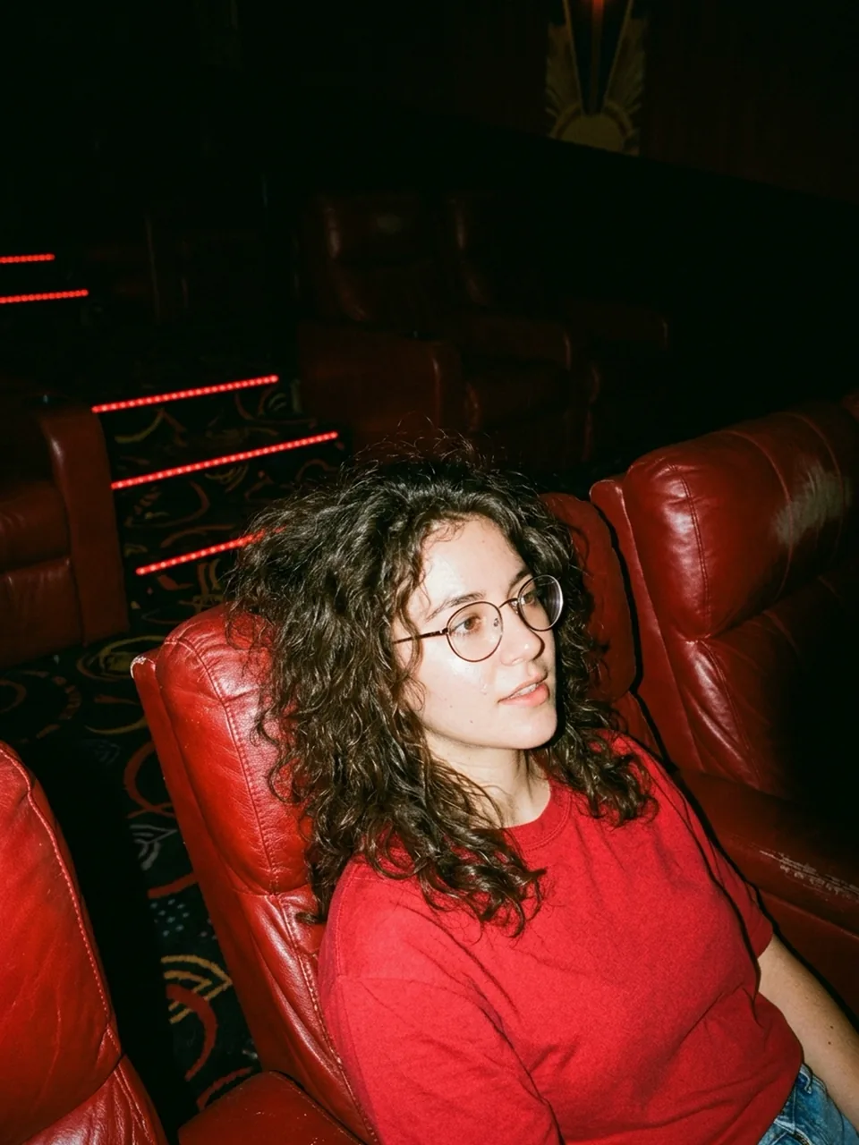 Candid direct-flash photo of a woman in a dark retro cinema lounge, generated with Nano Banana 2.1